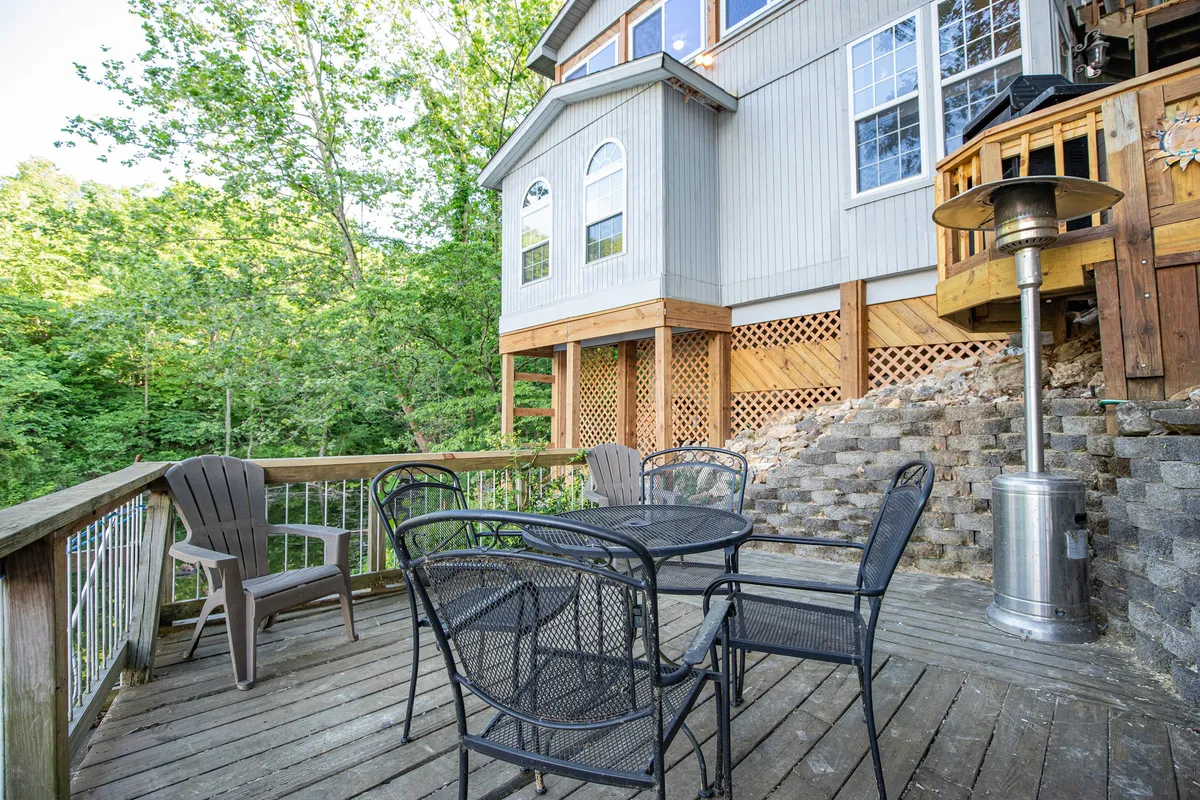 A comfortable outdoor seating area set in the midst of greenery, featuring a patio heater for cooler evenings. The arrangement welcomes guests to relax, entertain, and enjoy meals or conversations under the open sky.