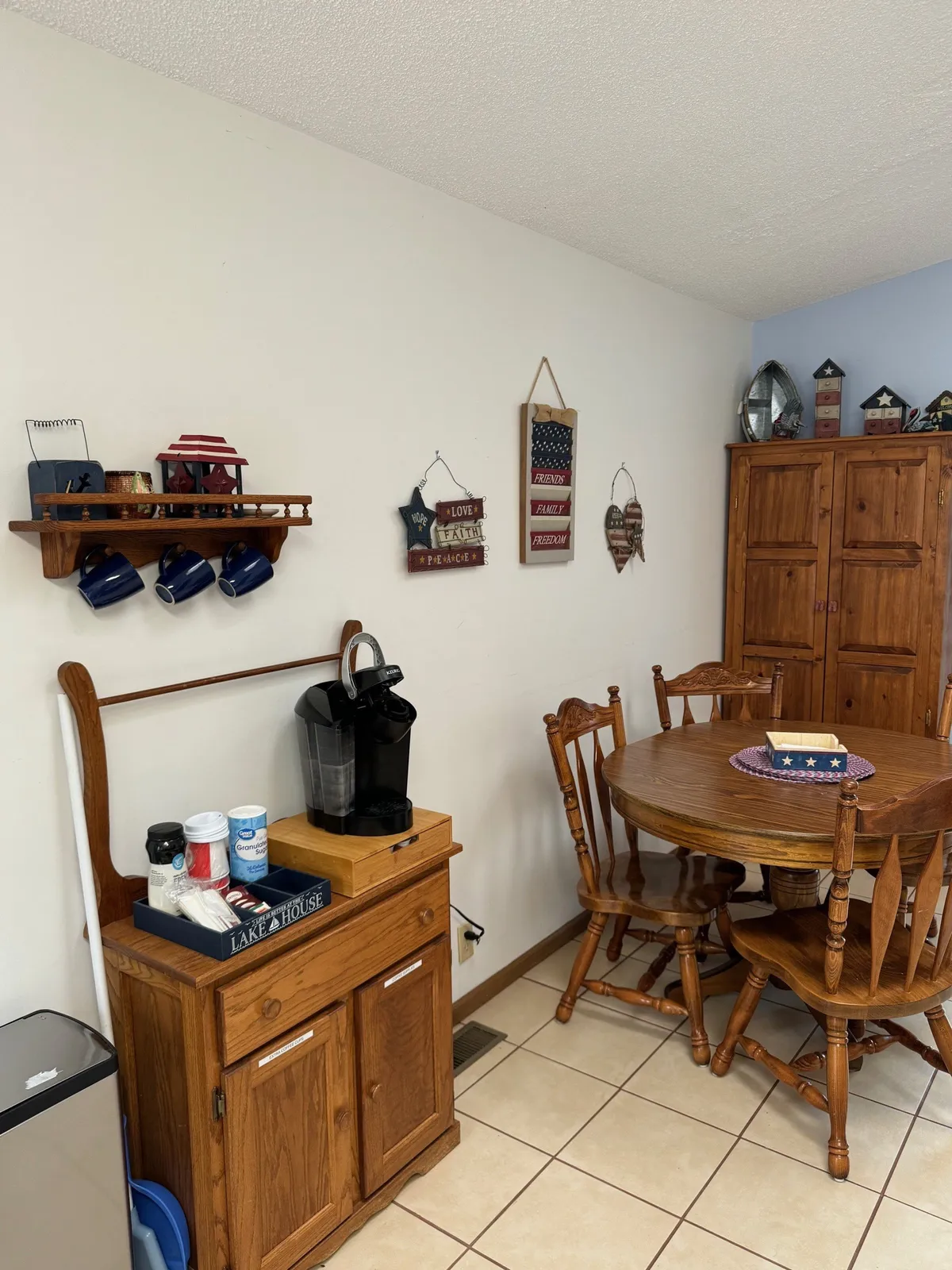 A warm, nostalgic dining area with a large wooden table, coffee station, comfortable chairs, and decorative wall hangings. The setting suggests a place where guests come together for meals, coffee breaks, and memorable celebrations, creating a sense of togetherness and shared stories.