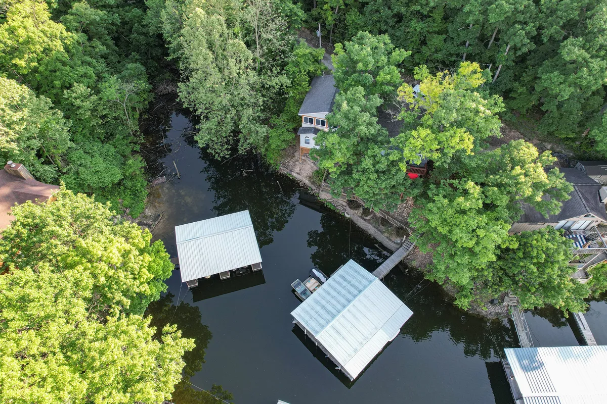 A tranquil lakeside scene with several houses, docks, trees, and the water, illustrating the unique cliffside neighborhood and its sense of community. The view conveys both privacy and the friendly, scenic atmosphere that the property offers.