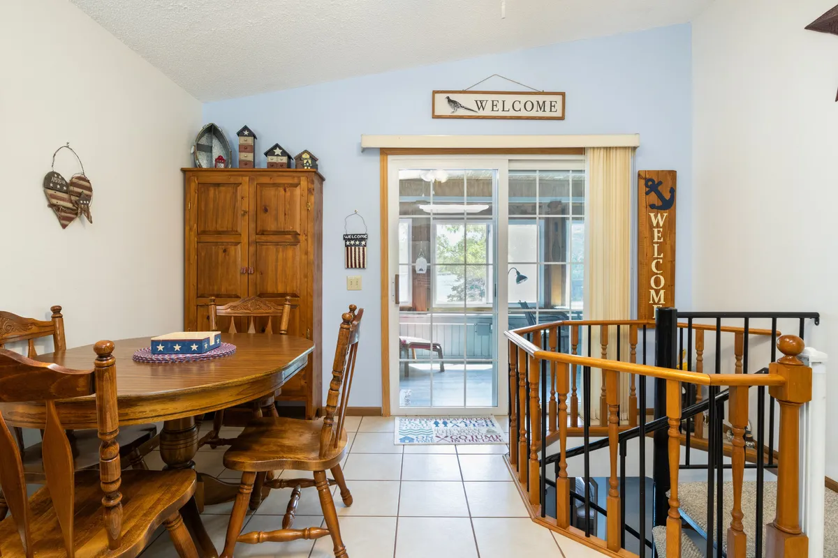 A warm, inviting interior scene with a spacious dining table, welcome signs, a spiral staircase, and a wooden cabinet. The setup encourages family meals, shared stories, and group activities after a day spent outdoors.