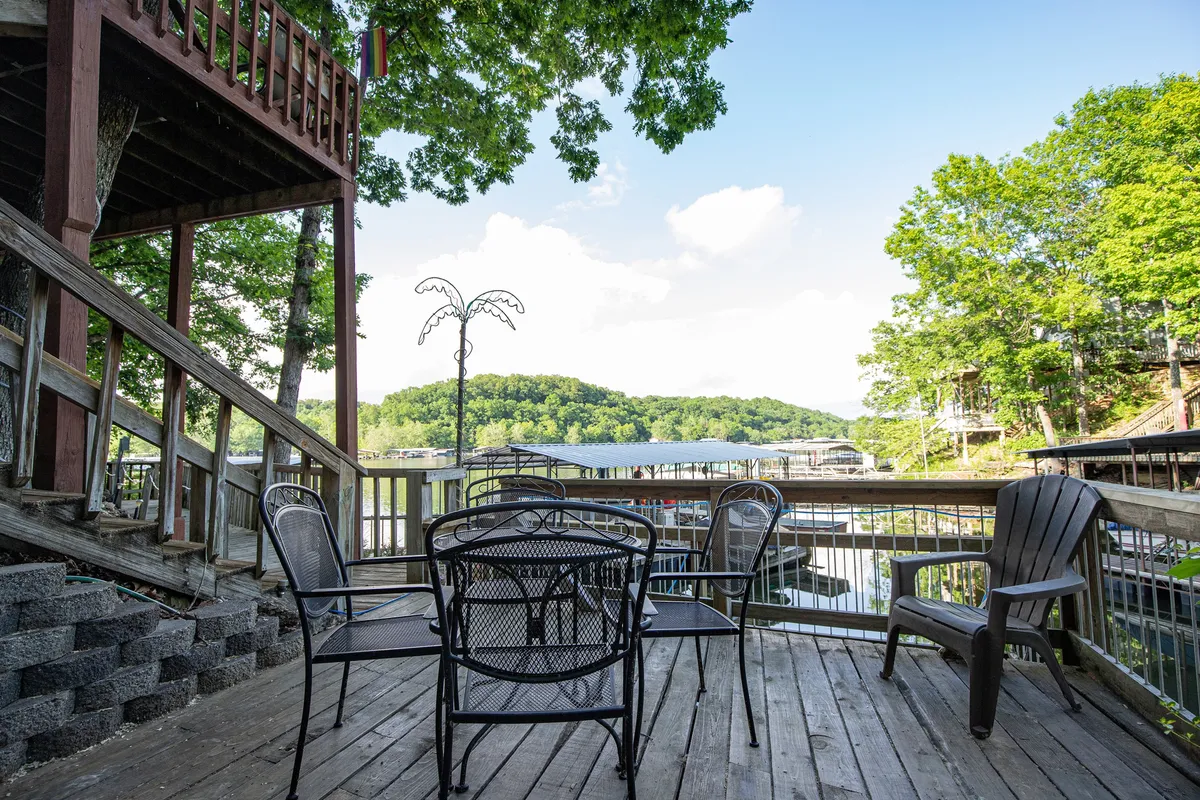 An exterior view of the deck featuring casual outdoor seating, with a stunning vista of the lake and surrounding trees beyond. The arrangement suggests opportunities for dining, relaxing, or simply soaking in the sunset, reinforcing the deck’s role as an extension of the living space.
